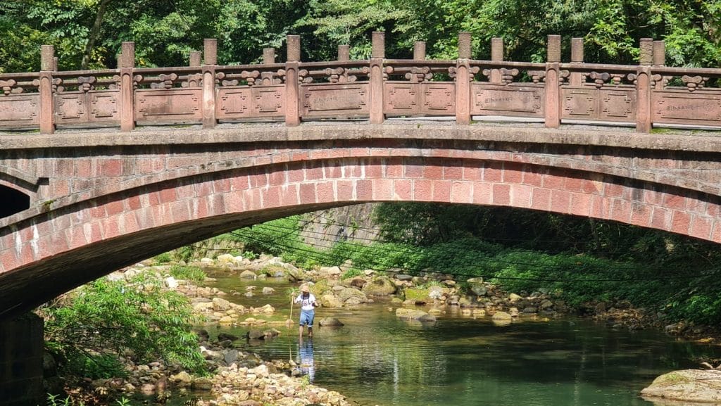 Person im Fluss unter alter Steinbrücke