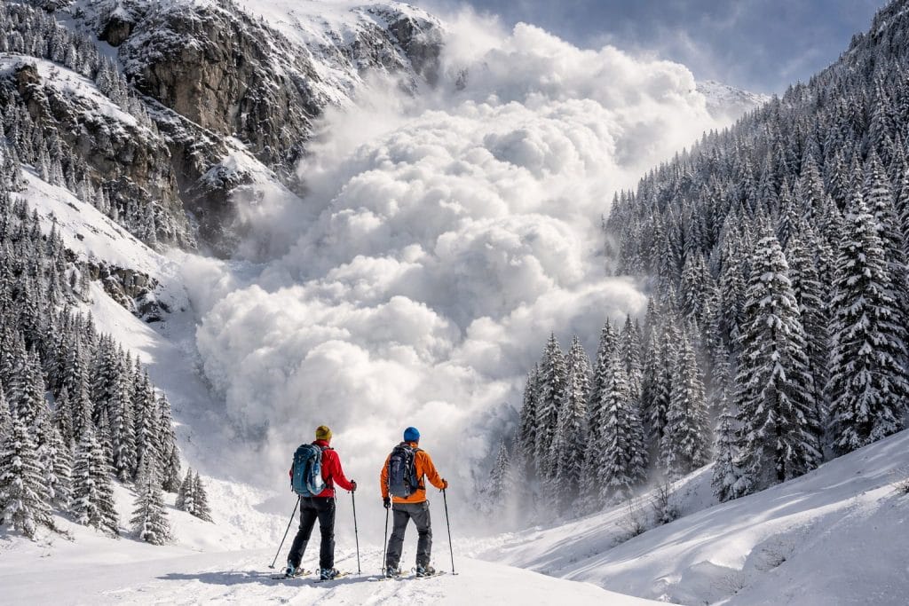 Skifahrer beobachten Schneelawine im Gebirge.