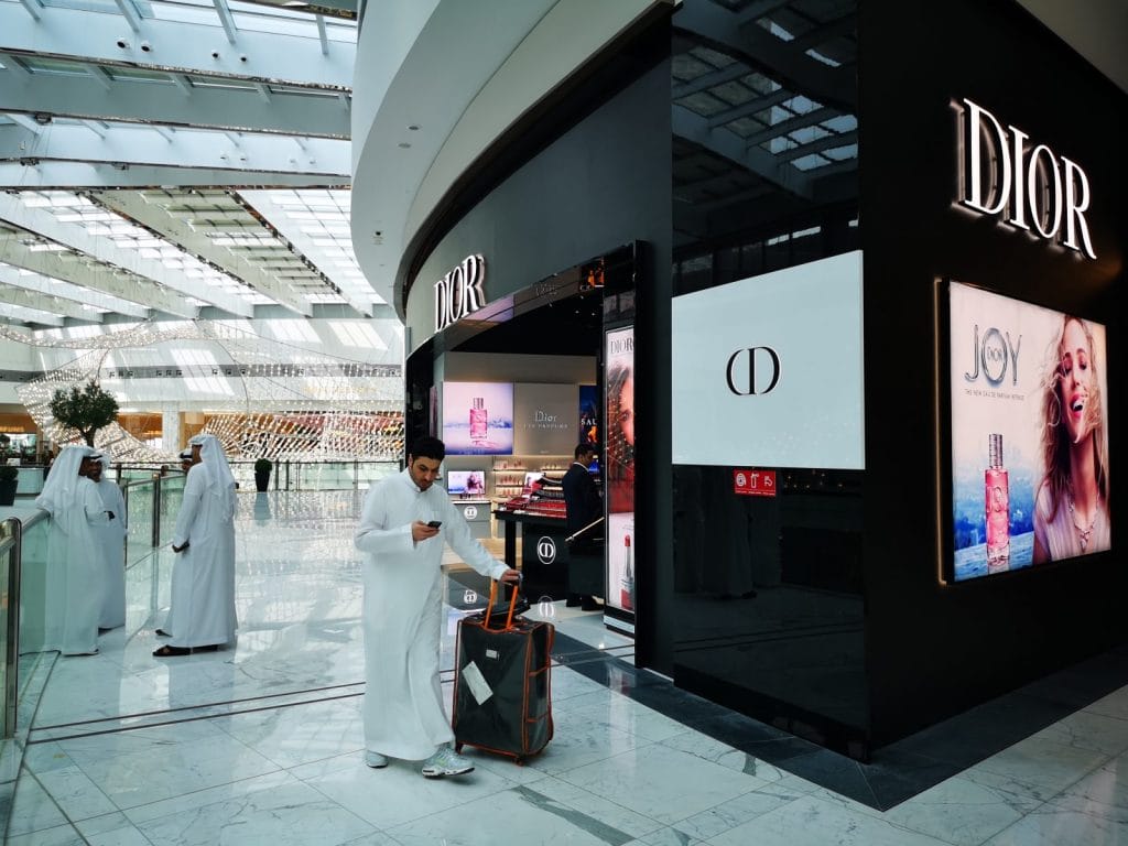 Person mit Koffer vor Dior-Geschäft im Einkaufszentrum.